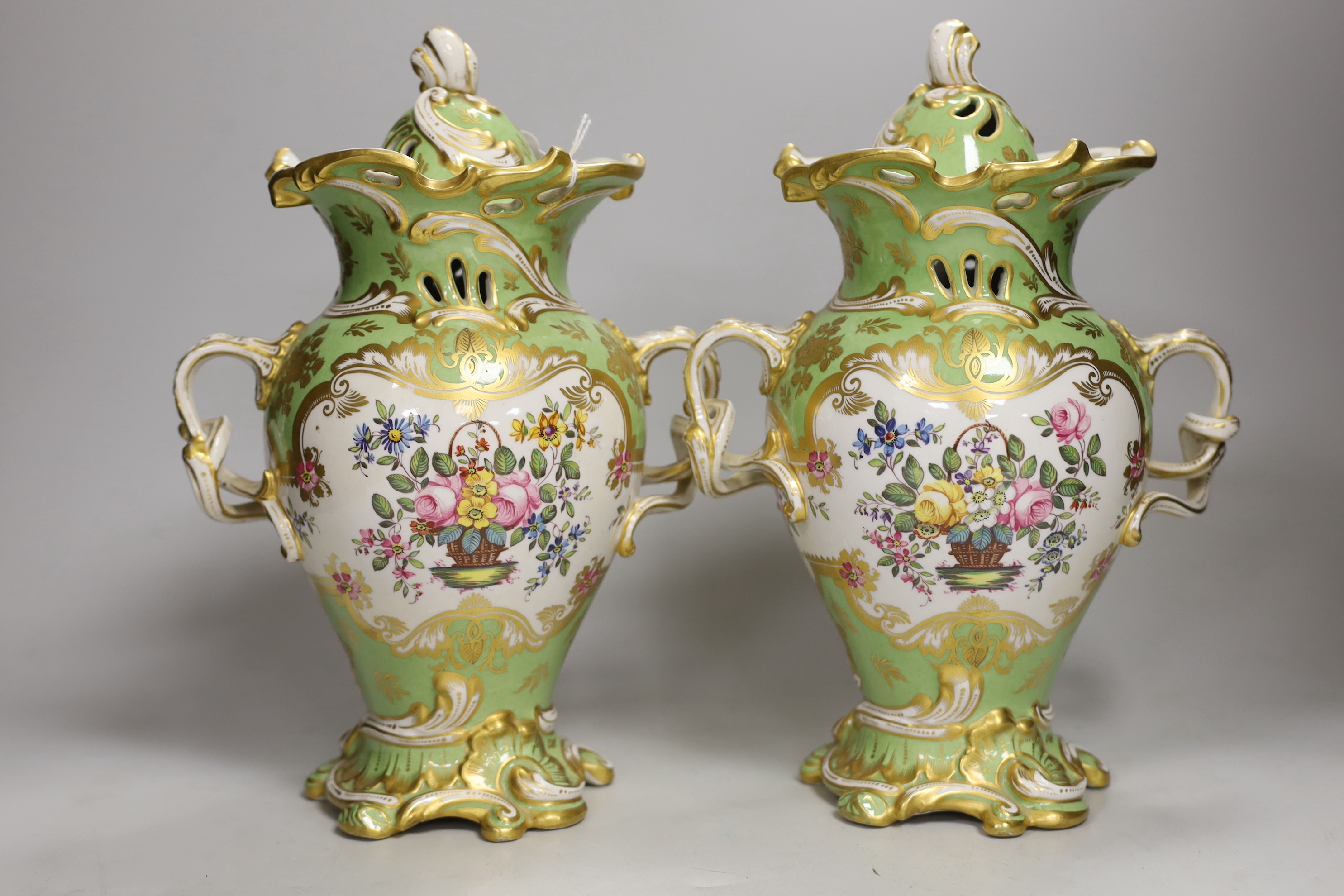 A pair of Rockingham style porcelain pot pourri vases, each of rococo form painted to each side with baskets of flowers, rare brown printed Rockingham griffin mark, 29cm high